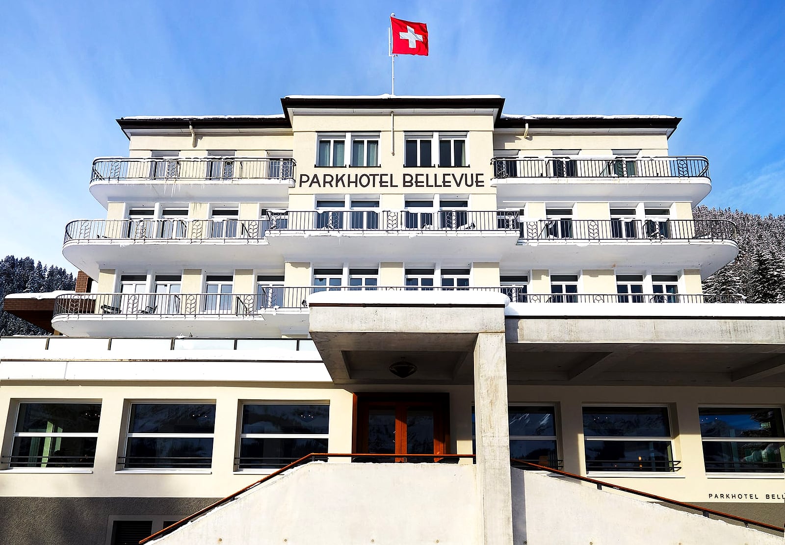 The Bellevue Parkhotel in Adelboden with the Swiss flag against a blue winter sky